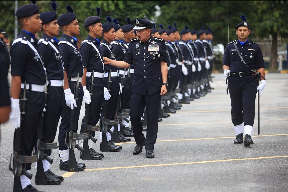 Muhamad Zaki (tengah) memeriksa barisan kehormat di IPK pada Selasa. - Foto PDRM