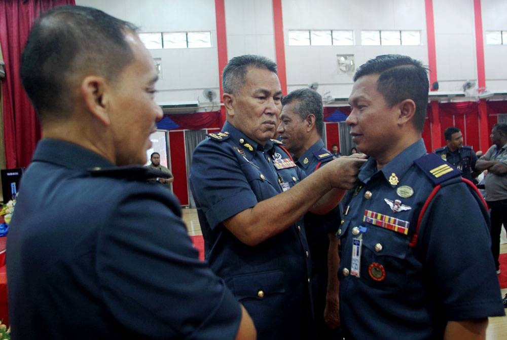 Pengarah Bomba Perak, Azmi Osman (tengah) menyempurnakan pemakaian tanda pangkat kepada Shahrul Nizam sempena Perhimpunan Bulanan dan Majlis Serah Terima Tugas Pengurusan Tertinggi Jabatan Bomba dan Penyelamat (JBPM) Perak di sini pada Selasa.