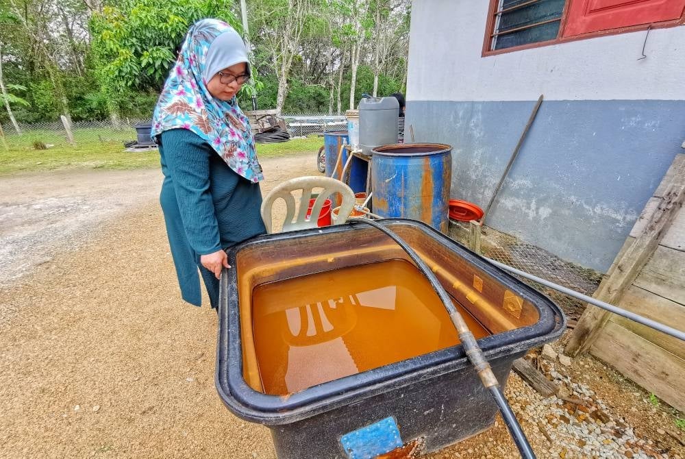 Hanani menunjukkan keadaan air boreng selepas ditakung yang terpaksa juga digunakan untuk mandi, membasuh pakaian serta pinggan mangkuk.