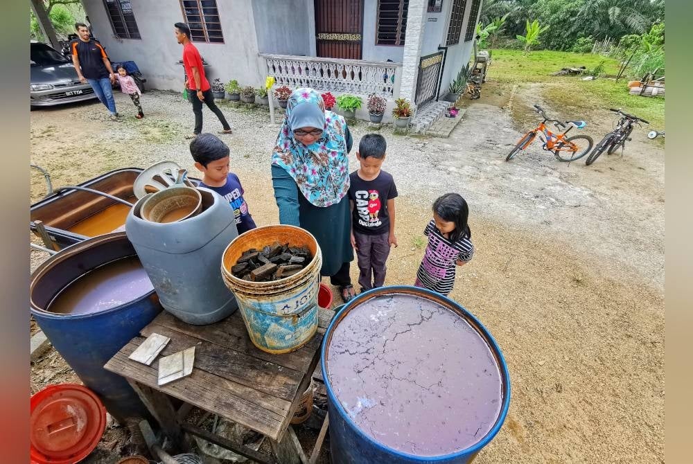 Hanani menunjukkan kualiti air boreng yang ditakung di belakang rumahnya di Kampung Pulau Manis, Jalan Telemong, Manir di Kuala Terengganu.