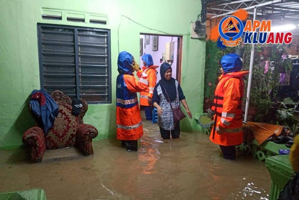 Anggota APM Kluang membantu memindahkan mangsa banjir. - Foto APM Kluang