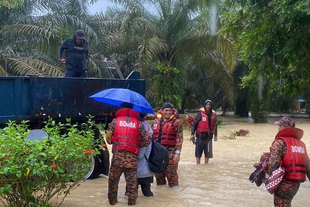 Anggota bomba turut mengawal keadaan ketika kerja-kerja memindahkan mangsa banjir di Kampung Sri Rambai Machap, Simpang Renggam pada Rabu. - Foto: Bomba
