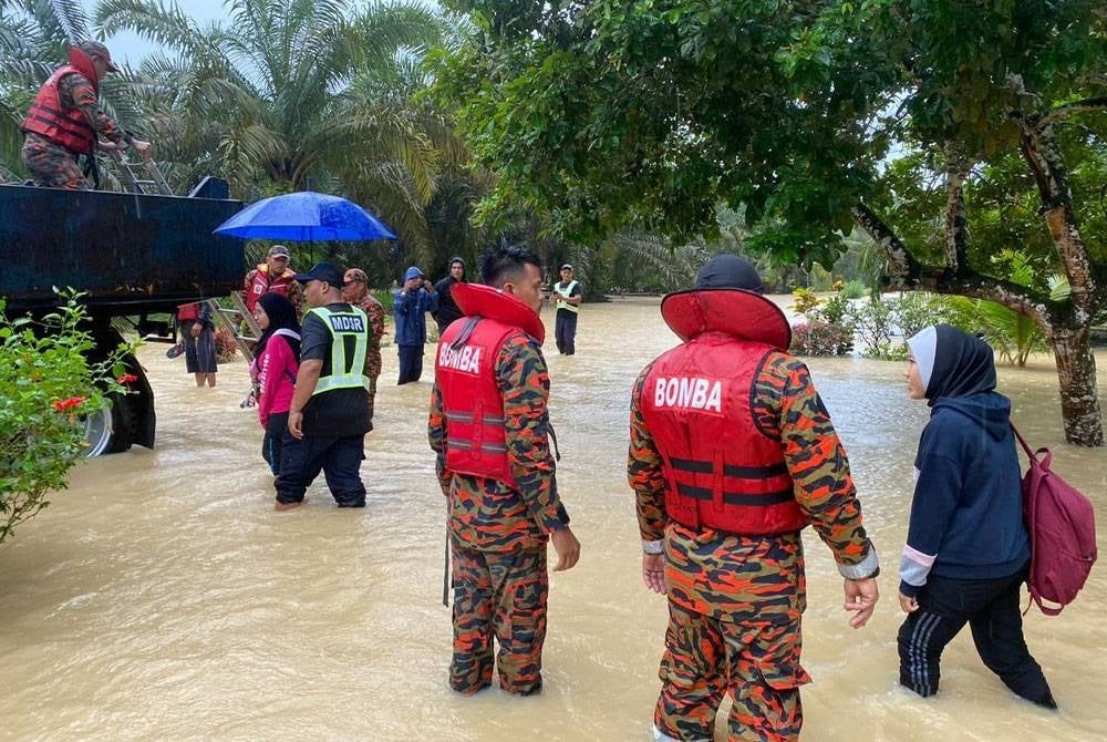 Mangsa banjir di Kampung Sri Rambai Machap, Simpang Renggam dibantu oleh anggota bomba ke PPS pada Rabu.