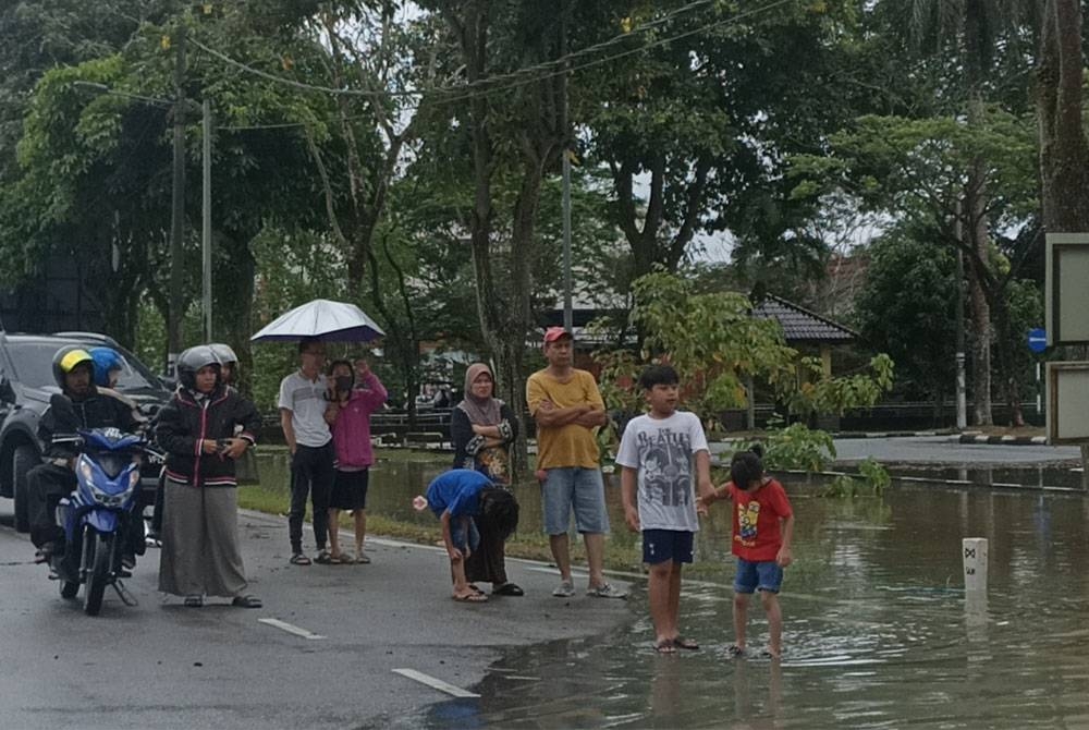 Orang ramai melihat keadaan banjir di kawasan bandar Kota Tinggi.