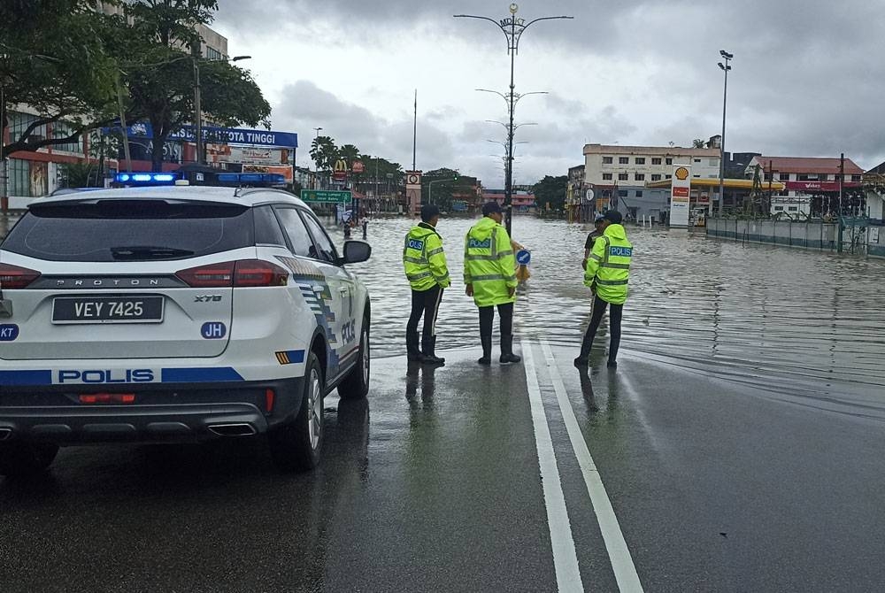 Anggota polis memantau kawasan bandar Kota Tinggi yang dilanda banjir.