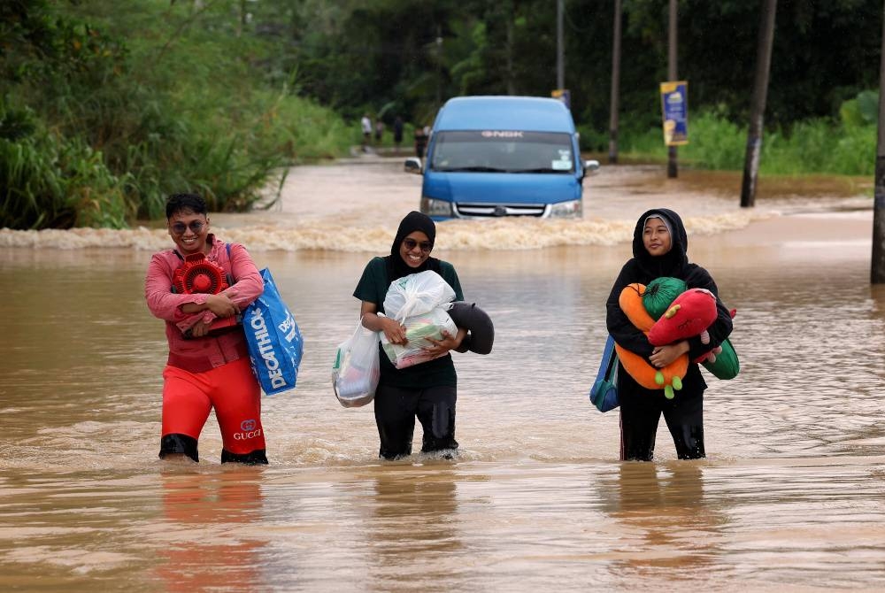 Orang ramai meredah banjir di laluan utama ke Kampung Kelantan di Kota Tinggi pada Rabu. - Foto Bernama