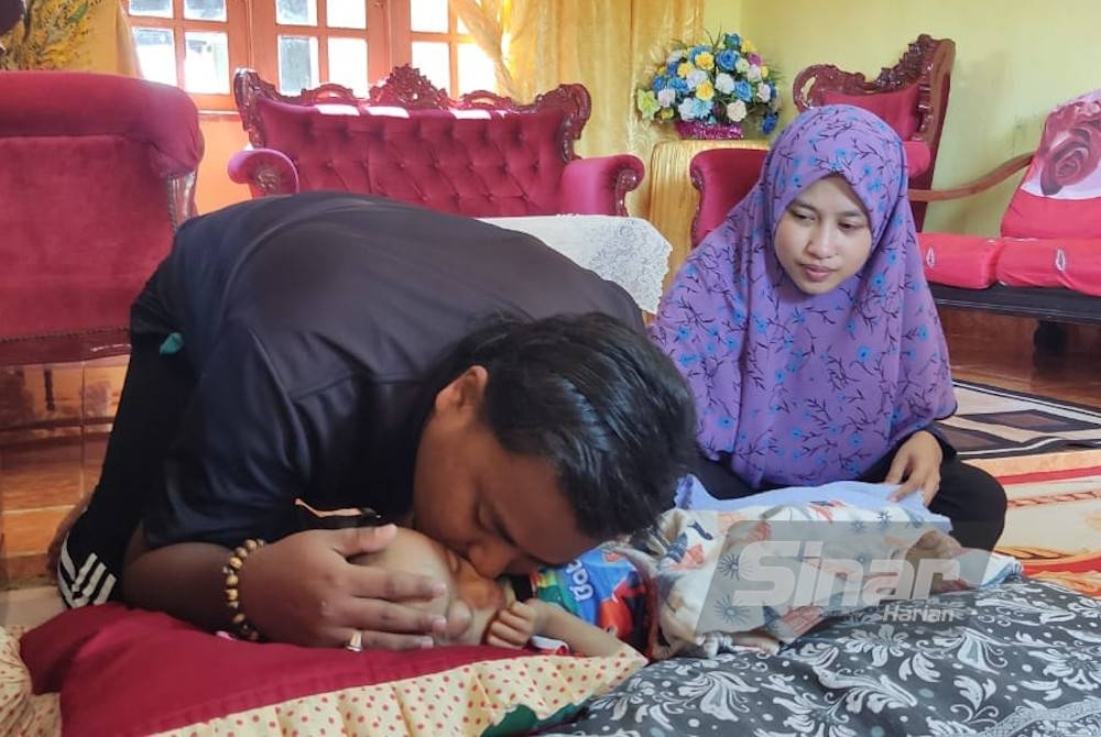 Abdul Rauf mencium Rafa Alauddin sambil diperhatikan oleh Noor Amira semasa ditemui di Kampung Pondok Kubang Rotan, Kuala Kedah baru-baru ini.