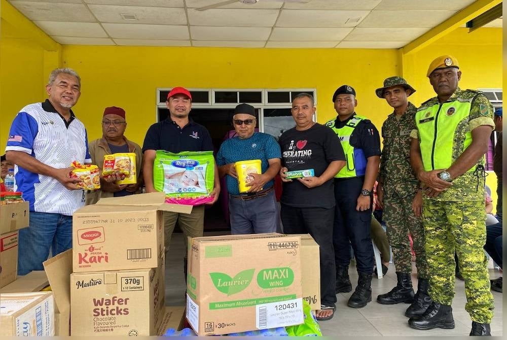 Hashim (kiri) dan Dr Zainizan (enam dari kanan) ketika menyampaikan sumbangan kepada mangsa banjir.