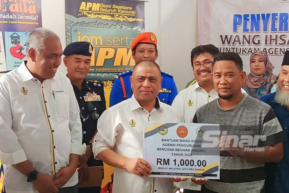 Saarani (dua dari kiri) menyempurnakan penyerahan bantaun wnag ehsan RM1,000 kepada mangsa banjir sempena Program Mesra Hari Bertemu Pelanggan di Arena Square Parit pada Khamis.