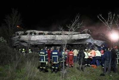 Anggota penyelamat cuba mengeluarkan mayat mangsa terperangkap dalam kereta api yang hangus terbakar di bandar Larissa. - Foto AFP