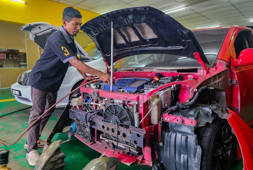 Mohammad Naim melihat kerosakan kereta akibat dimasuki air. - Foto Bernama