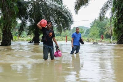 Penduduk Kampung Contoh Kahang, Kluang, Johor meredah banjir keluar dari kediaman yang ditenggelami air untuk ke Pusat Pemindahan Sementara (PPS) terdekat, ketika tinjauan pada Jumaat. - Foto: Bernama