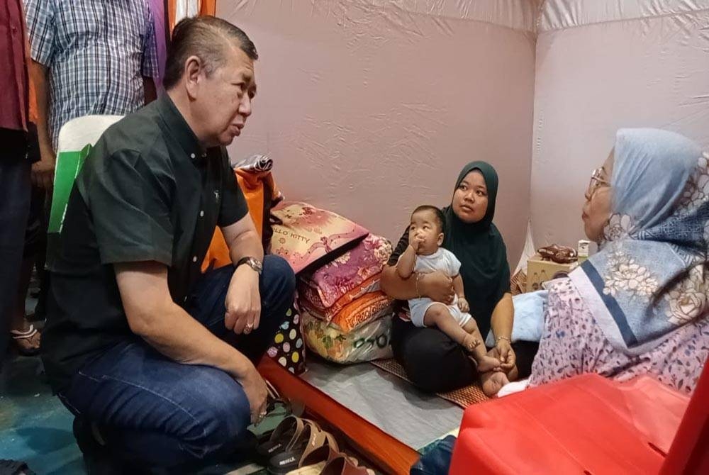 Salahuddin (kiri) bertanya khabar kepada salah seorang manga banjir di PPS Dewan Orang Ramai Parit Yaani pada Sabtu.