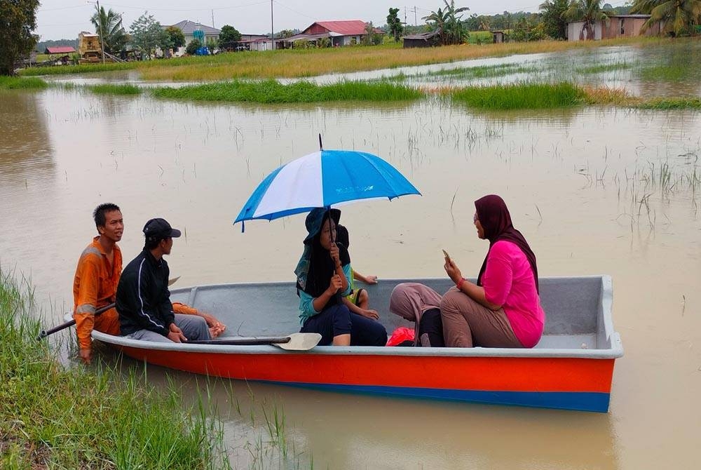 Nur Faezah (tiga,kiri) bersama ahli keluarganya menaiki sampan untuk melihat keadaan rumahnya di
Kampung Parit Seman Benteng pada Sabtu.