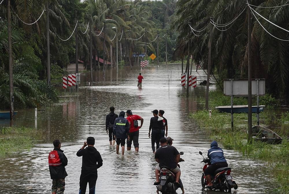 Penduduk setempat meninjau keadaan banjir yang masih belum surut berikutan hujan berterusan ketika tinjauan di Kampung Saujana, Lenga, Muar pada Sabtu. - Foto: Bernama