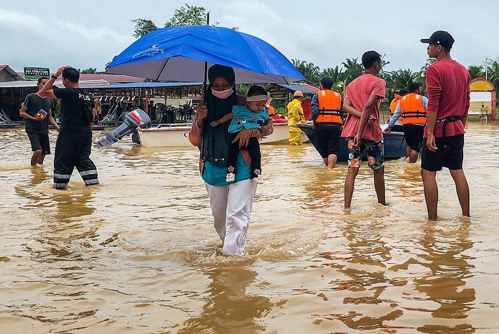 Mangsa banjir mengendong anak kecilnya selepas keluar dari Kampung Parit Warijo, Sri Medan,Batu Pahat yang dinaiki air sejak malam tadi ketika tinjauan pada Sabtu. - Foto: Bernama