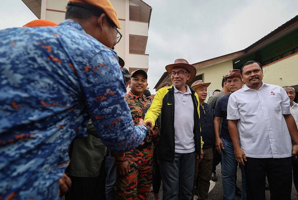 Perdana Menteri dan Menteri Kewangan Datuk Seri Anwar Ibrahim beramah mesra bersama petugas barisan hadapan selepas melawat mangsa banjir di Pusat Pemindahan Sementara (PPS) Sekolah Kebangsaan Gemereh hari ini.