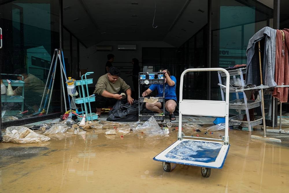 Pekerja sebuah premis perniagaan melakukan kerja-kerja pembersihan selepas terjejas ekoran banjir yang melanda baru-baru ini. - Foto Bernama