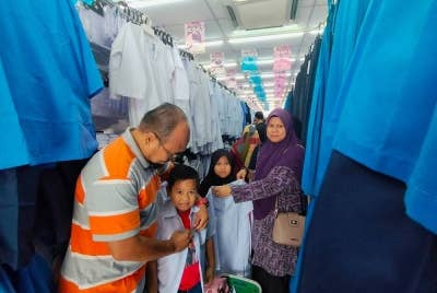 Rabihah (kiri) bersama suaminya, Mior Ahmad Khusairi,47, membeli kelengkapan sekolah empat anaknya di sebuah pasar raya di bandar ini pada Ahad.