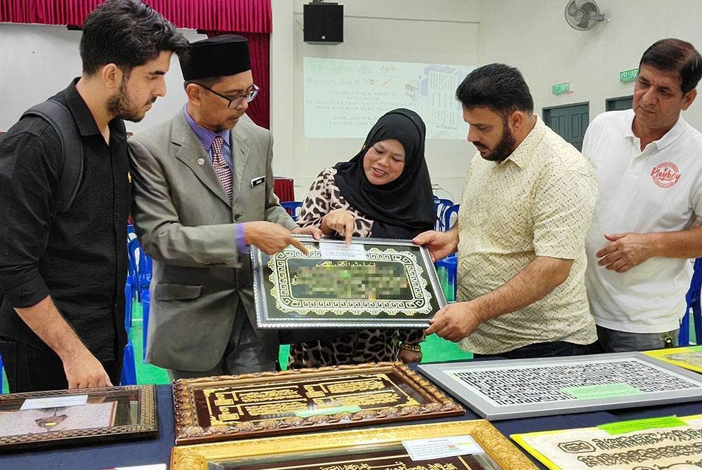 Ahmad Husaini(dua dari kiri) menunjukkan kesilapan pada ayat al-Quran pada perhiasan khat yang terdapat di pasaran kepada peniaga Nilai 3