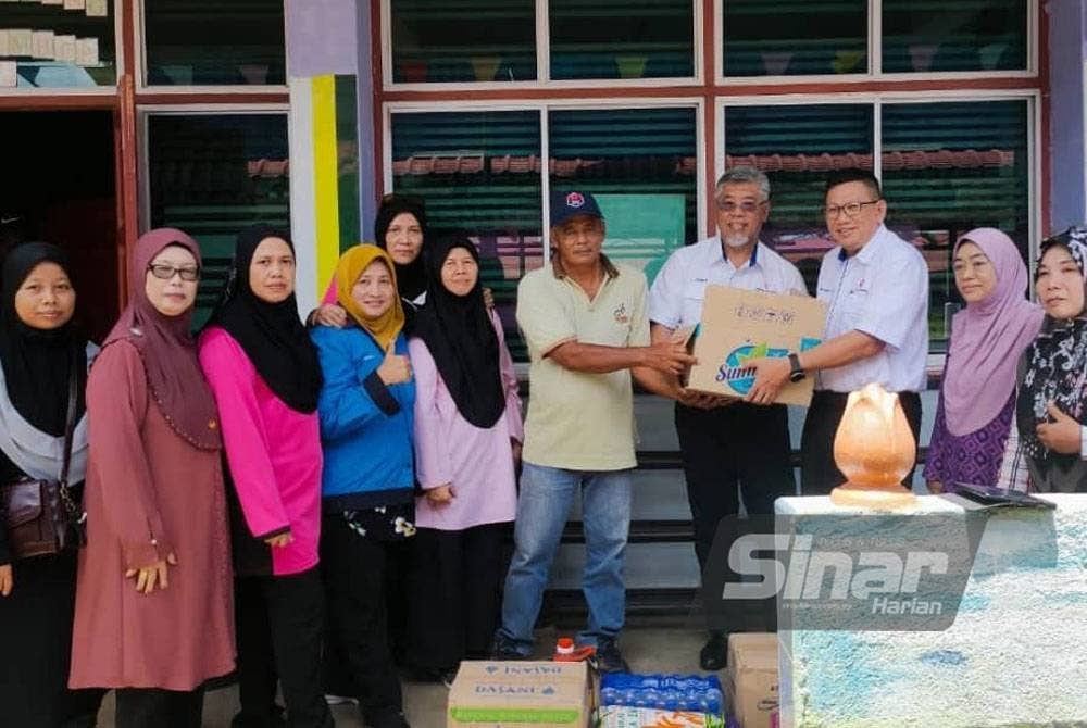 Shamsul menyerahkan bantuan kotak makanan TNB kepada mangsa banjir di Pusat Pemindahan Sementara (PPS) Sekolah Agama Seri Maimon, Batu Pahat, Johor.