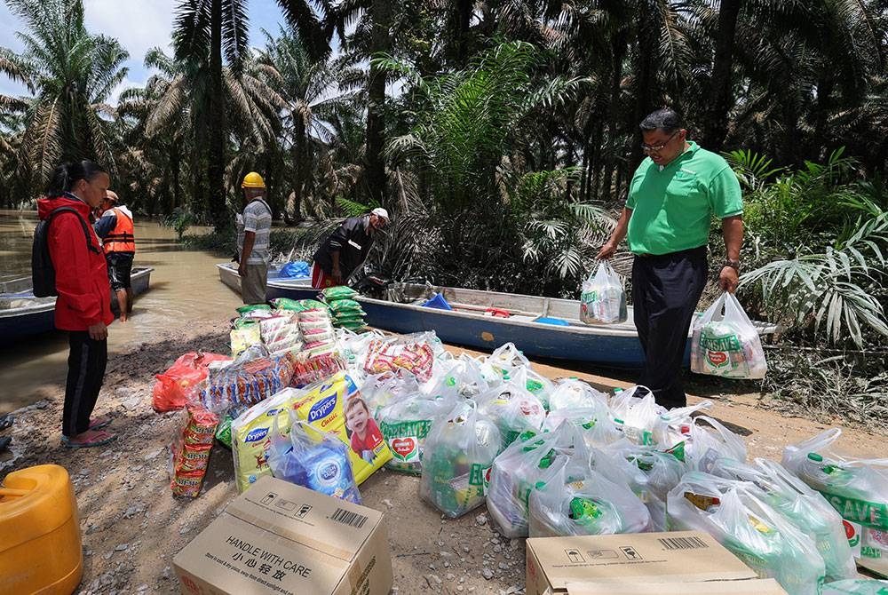 Mas Imran (kanan) memeriksa barang bantuan yang akan diberikan kepada penduduk Kampung Orang Asli Sungai Peroh, Kahang. - Foto Bernama