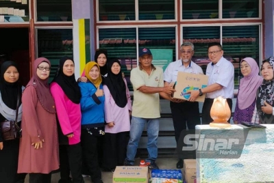 Shamsul menyerahkan bantuan kotak makanan TNB kepada mangsa banjir di Pusat Pemindahan Sementara (PPS) Sekolah Agama Seri Maimon, Batu Pahat, Johor.