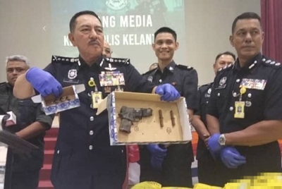 Muhamad Zaki menunjukkan pistol tiruan yang dirampas dalam serbuan di Kampung Gong Datok, Pasir Puteh.
