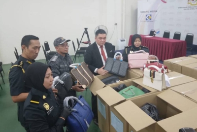 Ariffin (dua dari kanan) menunjukkan antara rampasan barang tiruan dalam serbuan di Jalan Petaling, Kuala Lumpur Ahad lalu.