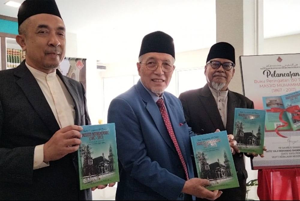 Mohamad Shukri (tengah) menunjukkan buku pada Majlis Pelancaran Buku Peringatan 150 Tahun Masjid Muhammadi, Kota Bharu pada Rabu.