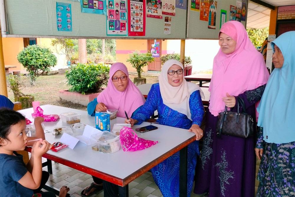 Kalsom (dua dari kiri) bersama mangsa banjir di SK Sungai Rambai pada Rabu.