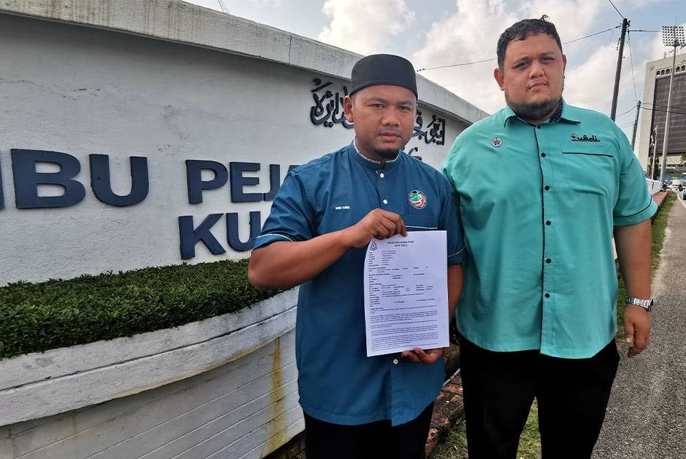 Mohd Harun (kiri) membuat laporan polis di IPD Kuala Terengganu mengenai tulisan di sebuah portal yang didakwa berunsur fitnah terhadap Presiden Pas, Tan Sri Abdul Hadi Awang.