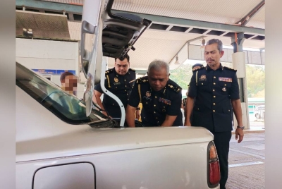 Aris (dua dari kanan) melakukan pemeriksaan ke atas kenderaan yang keluar dari Malaysia di ICQS Pengkalan Hulu pada Khamis.