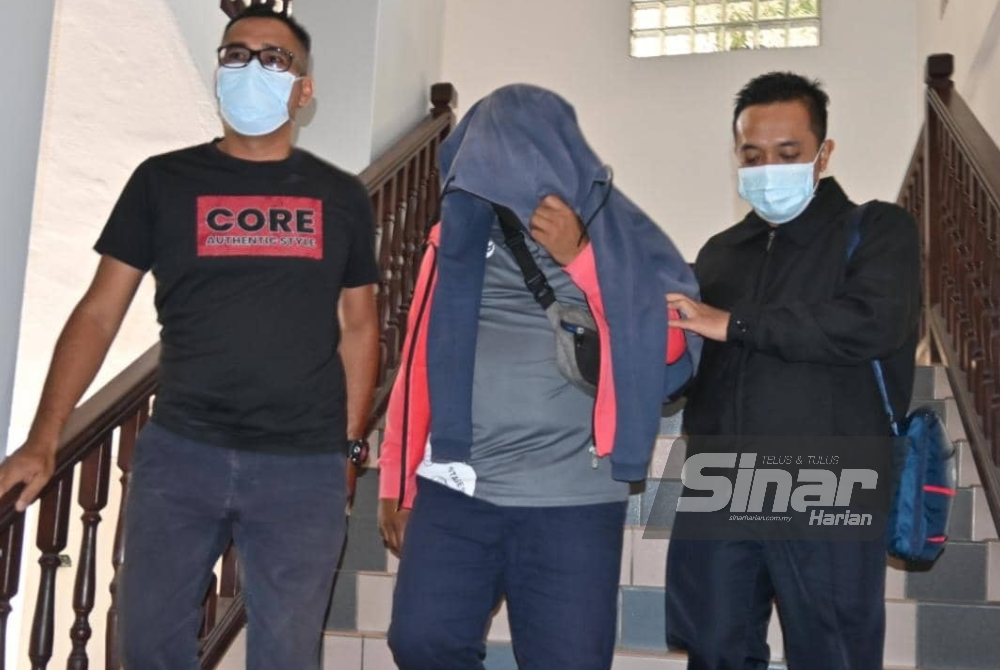 Che Fazdlie Izwan (tengah) ketika dibawa keluar dari Mahkamah Seksyen Melaka pada Jumaat.