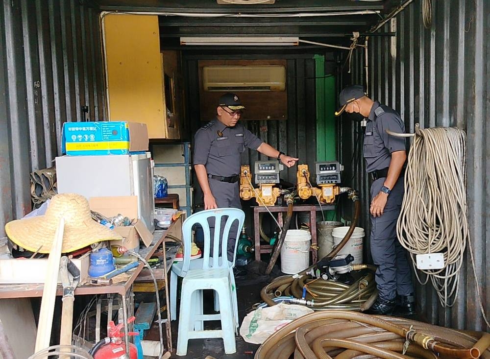 Muhamad Radzi (kiri) menunjukkan peralatan yang digunakan untuk menyedut dan memindahkan diesel yang ditemui dalam stor berhampiran.