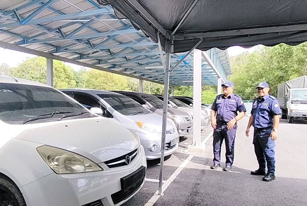 Mohammad Hafiz (kiri) menunjukkan kenderaan yang dirampas.