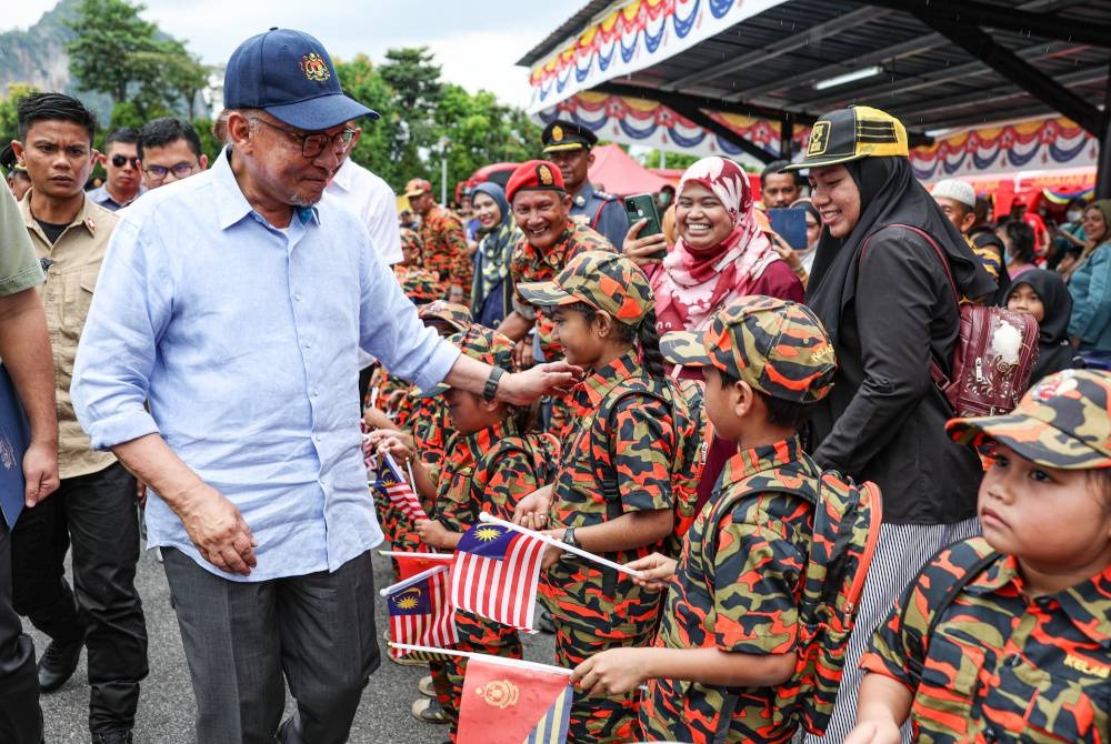 Anwar menyantuni anggota bomba cilik Jabatan Bomba dan Penyelamat Malaysia ketika hadir bagi merasmikan Balai Bomba dan Penyelamat Tambun di balai tersebut pada Sabtu. - Foto Bernama