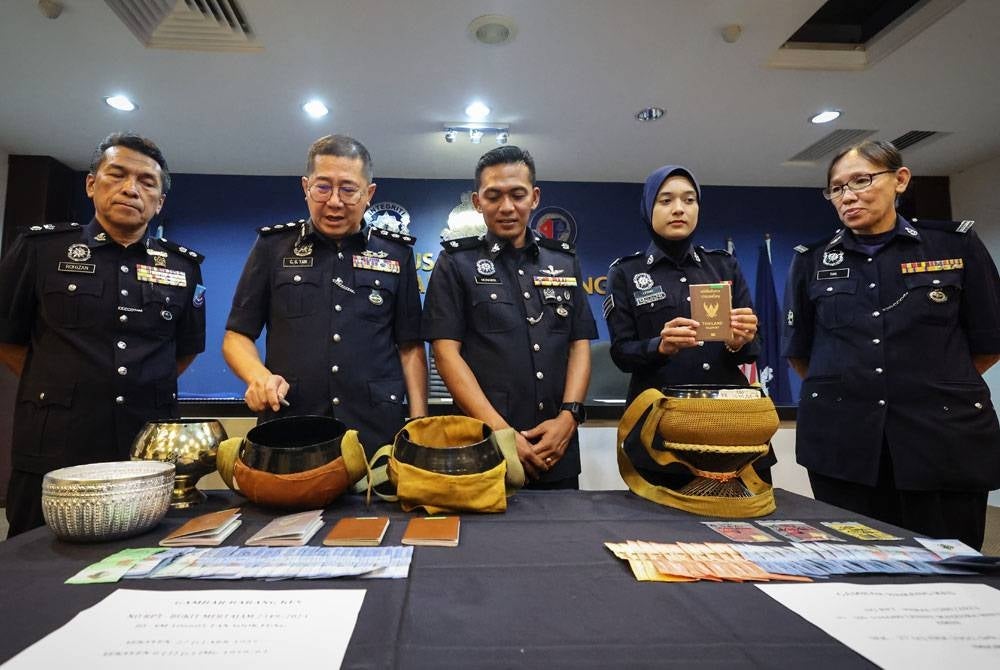 Cheng San (dua dari kiri) menunjukkan bekas mangkuk dan wang tunai yang dirampas. - Foto Bernama