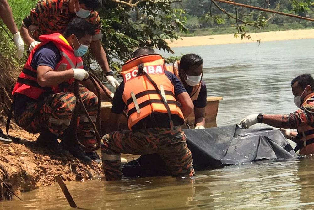 Anggota keselamatan menaikkan mayat seorang lelaki yang dijumpai terapung berhampiran tongkang mesin penyedut pasir di Sungai Kuala Berang, dekat Kampung Gaung, di Hulu Terengganu, pada Isnin. Foto: PDRM