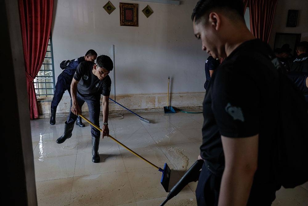 Anggota Polis Diraja Malaysia dari Balai Polis Yong Peng sedang giat bersihkan salah sebuah rumah mangsa banjir ketika tinjauan di sekitar perkampungan di Yong Peng pada Isnin. - Foto Bernama