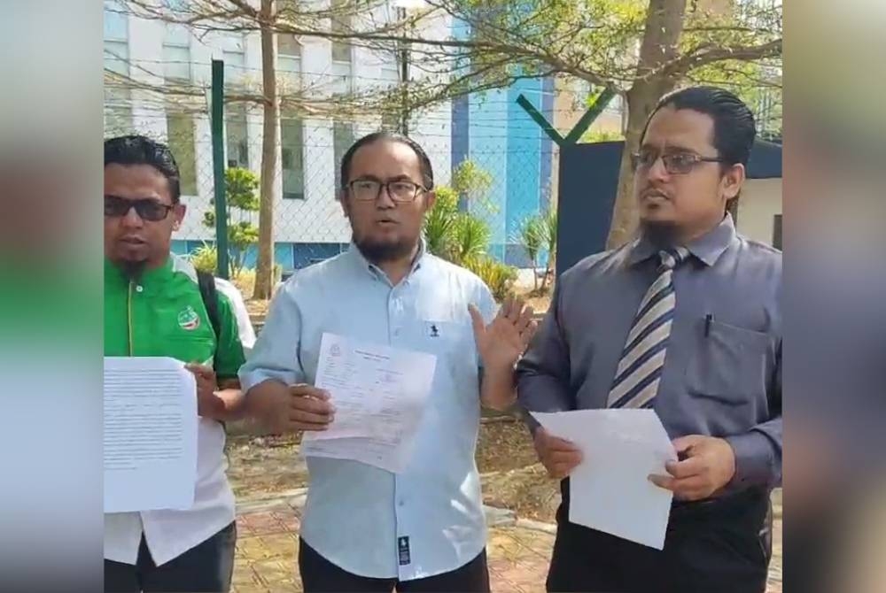 Nasrun (tengah) bersama Ku Abd Muhyi (kanan) menunjukkan laporan polis dibuat di Ibu Pejabat Polis Daerah (IPD) Kota Setar, pada Selasa.