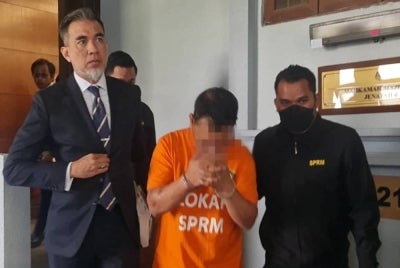 'Datuk Roy' (tengah) dibawa ke Mahkamah Majistret Kuala Lumpur pada Selasa oleh anggota SPRM dengan ditemani Fahmi (kiri).