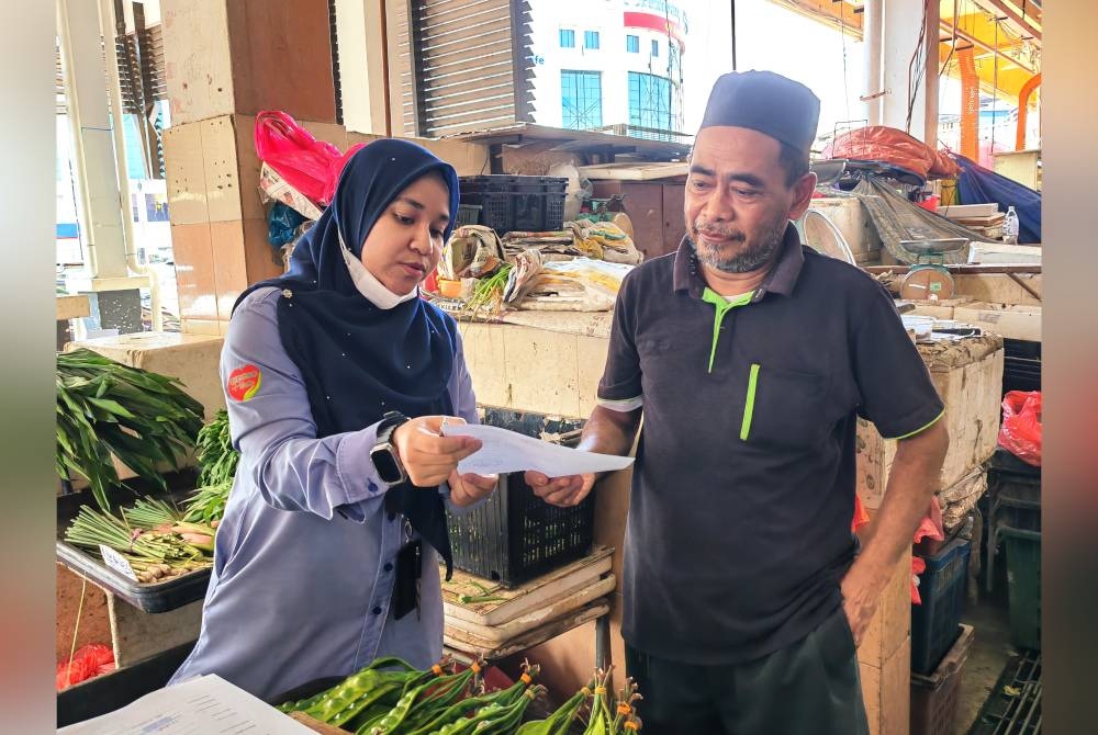 Azman mendengar penerangan berkenaan caruman orang bekerja sendiri daripada kakitangan Perkeso.