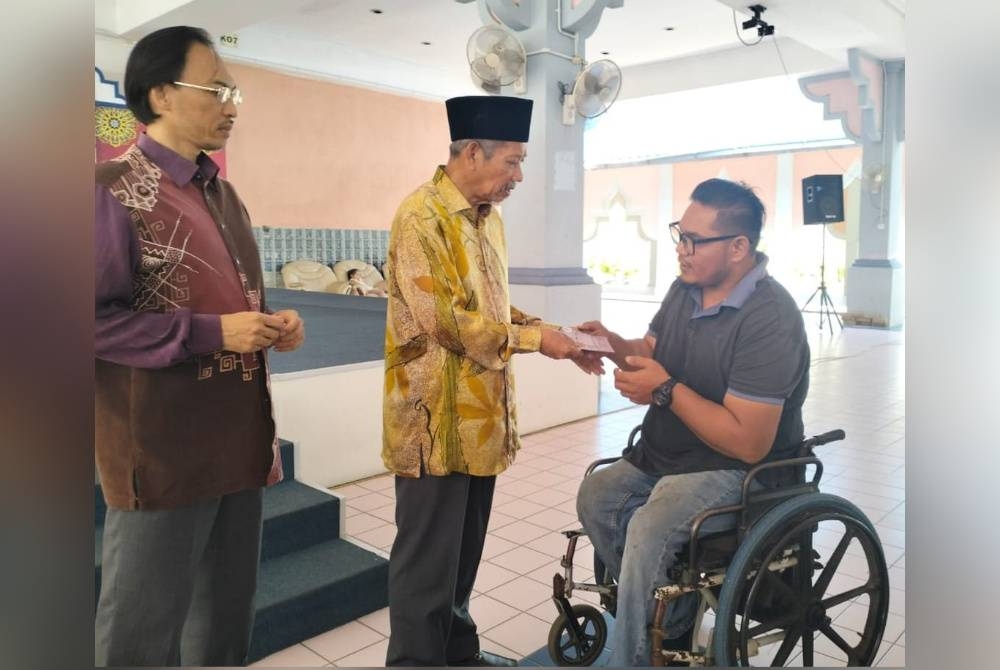 Shaikh Harun (tengah) menyampaikan bantuan zakat sempena Ramadan kepada salah seorang penerima pada Khamis.