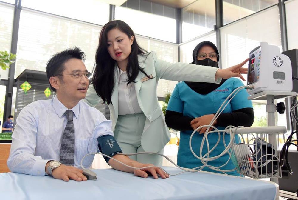 Le Dr Diana Tan (au centre) explique à Leong Yap (à gauche) l'utilisation des tensiomètres, parmi les établissements de santé fournis au Sunsuria Care Hub.