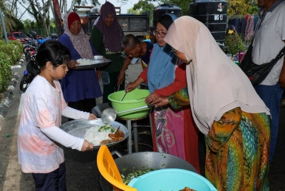 Mangsa banjir, Suriyani Arbain, 57, (dua dari kanan) bersama Noridah Arbain, 63, (kanan) menyeduk lauk makanan tengah hari kepada mangsa banjir di PPS Dewan Orang Ramai Sri Medan, Batu Pahat pada Rabu. - Foto Bernama
