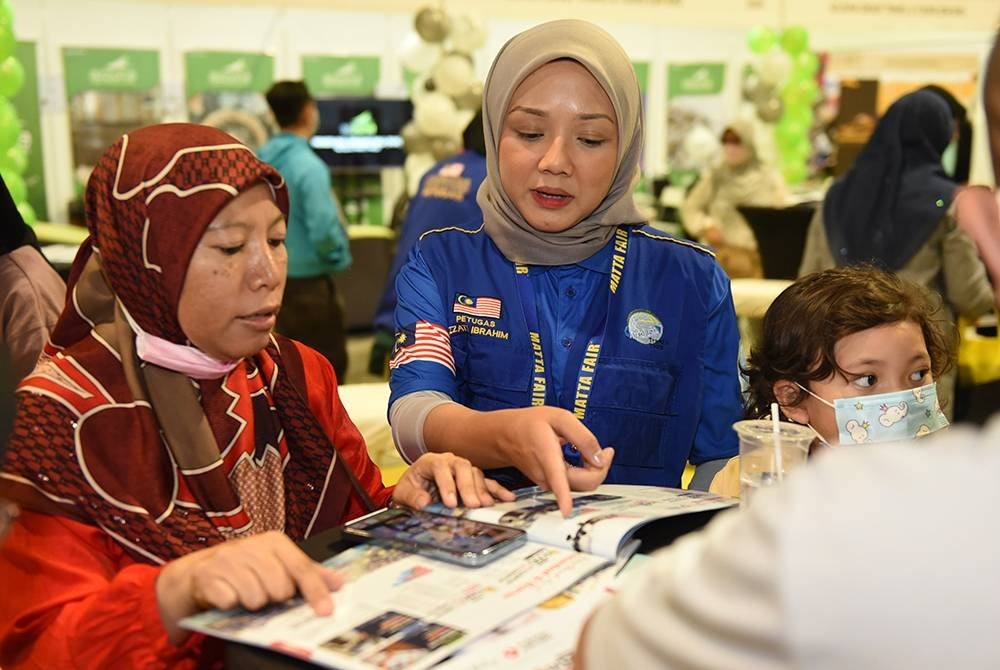 Izzati sedang melayan pengunjung yang hadir di reruai Andalusia Travel & Tours Sdn Bhd ya di MATTA Fair 2023, MITEC, Kuala Lumpur pada jumaat. - FOTO MOHD RAFIQ REDZUAN