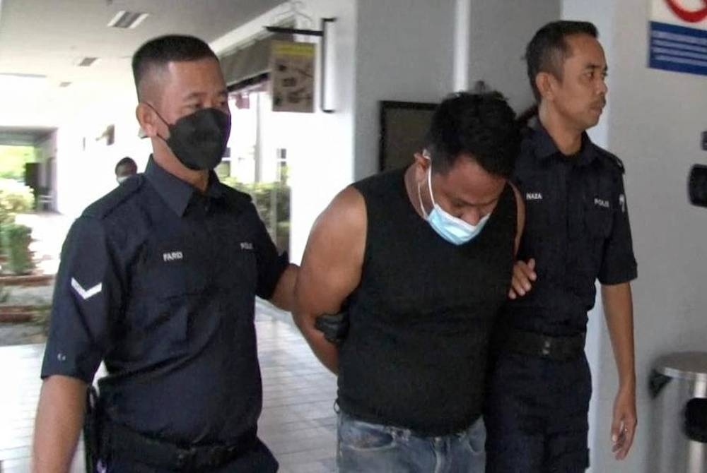 Tertuduh (tengah) dihadapkan ke Mahkamah Seksyen Melaka pada Jumaat atas pertuduhan cuba membunuh pegawai kanan polis.