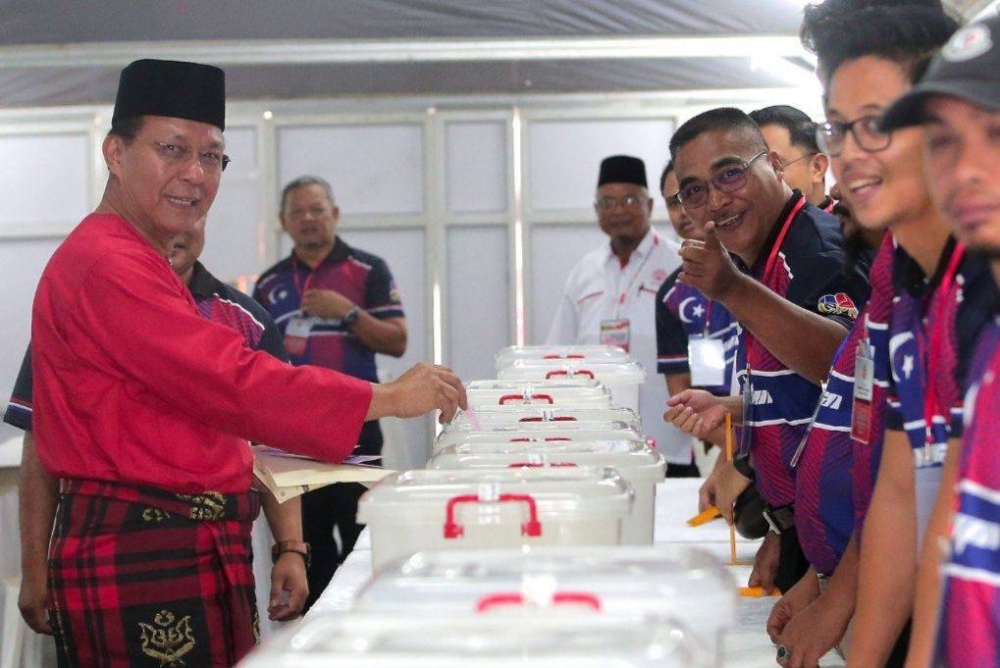 Hasni (kiri) membuang undi di Dewan Jubli Intan Pontian pada Sabtu.