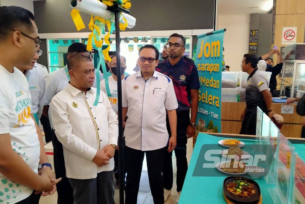 Saarani (deuxième à partir de la gauche) regarde le menu Rahmah qui a été présenté lors de la cérémonie d'ouverture de la Journée des consommateurs au niveau de l'État de Perak 2023 au supermarché Bercham de Lotus dimanche.